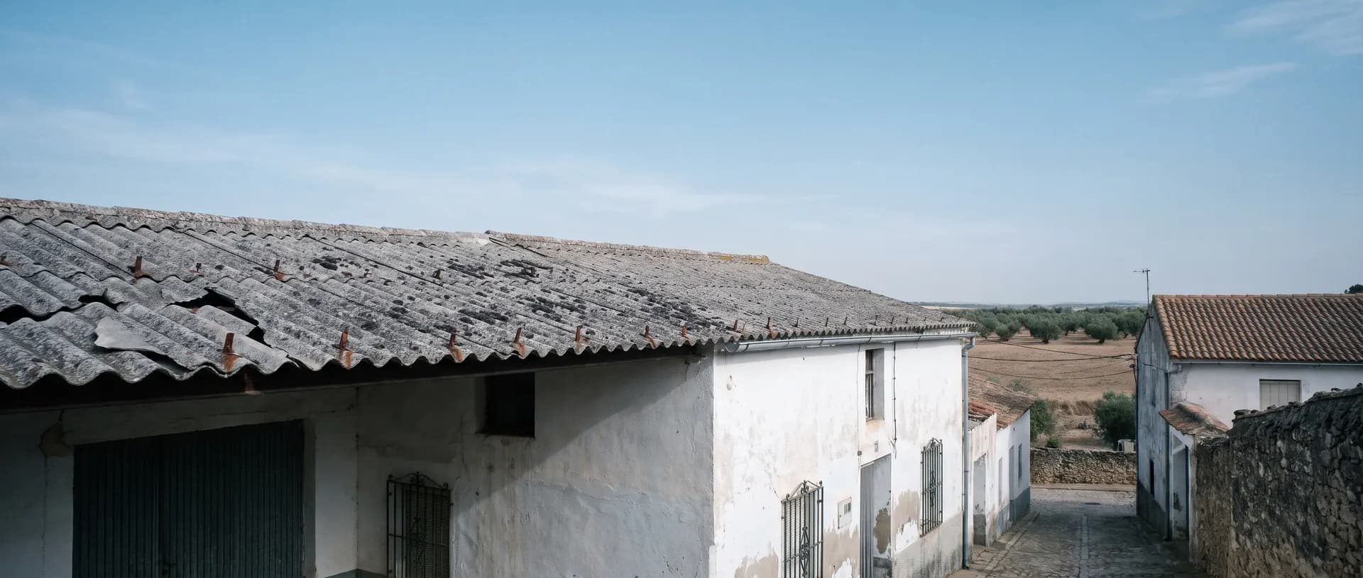 Casa encalada de pueblo con un tejado de uralita gris envejecido (imagen generada con IA)
