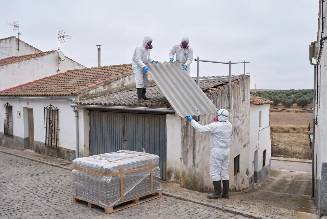 Operarios con mono y mascarilla bajan una placa de fibrocemento entera de un garaje (imagen generada con IA)